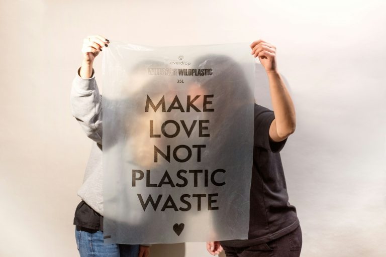 two people holding a sign that says make love not plastic waste