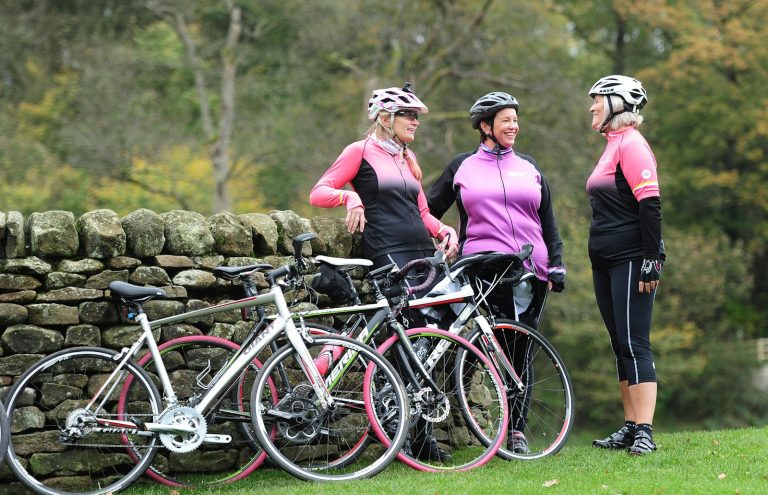 a group of women standing next to each other near a stone wall