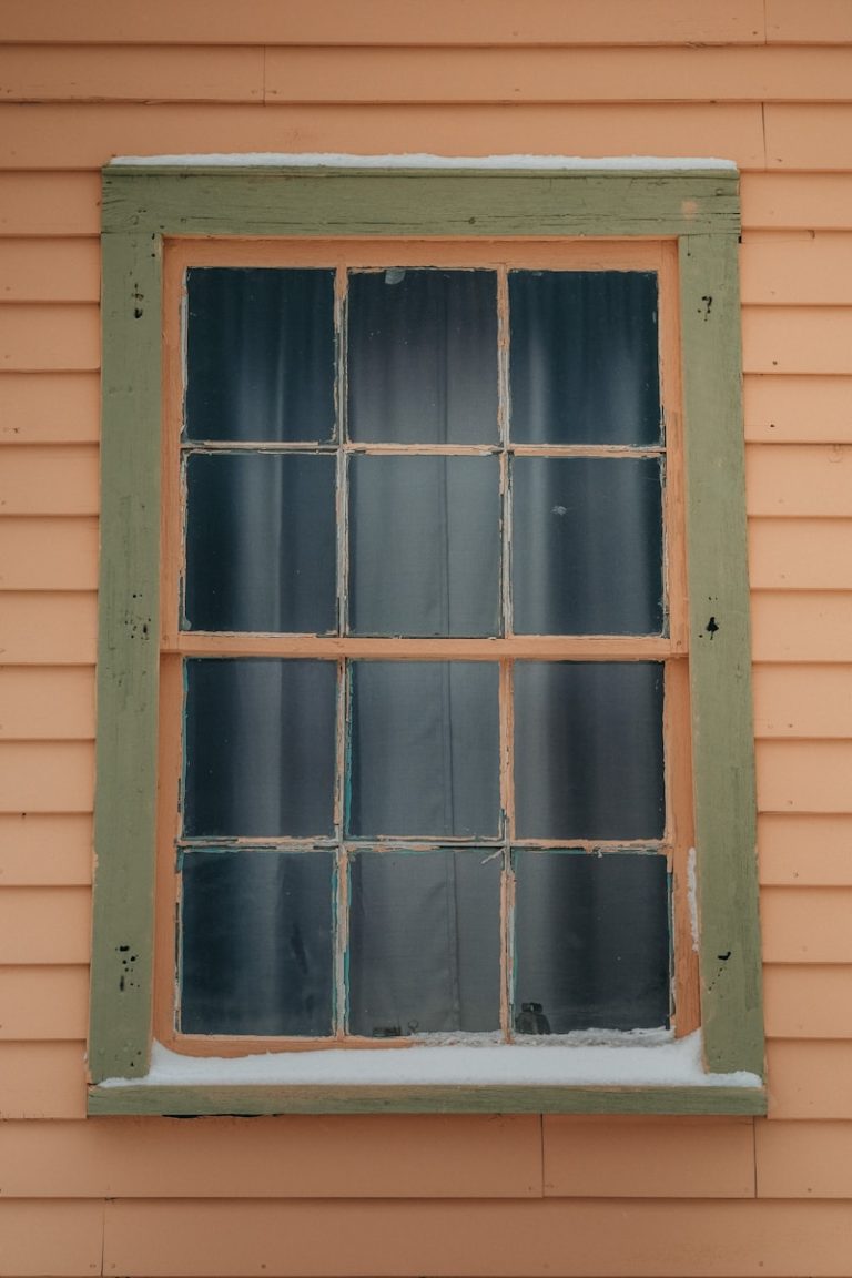 a window with a green frame on the side of a building