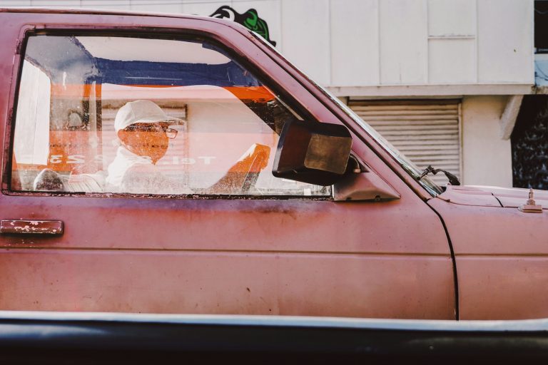 a man sitting in the driver's seat of a pink truck